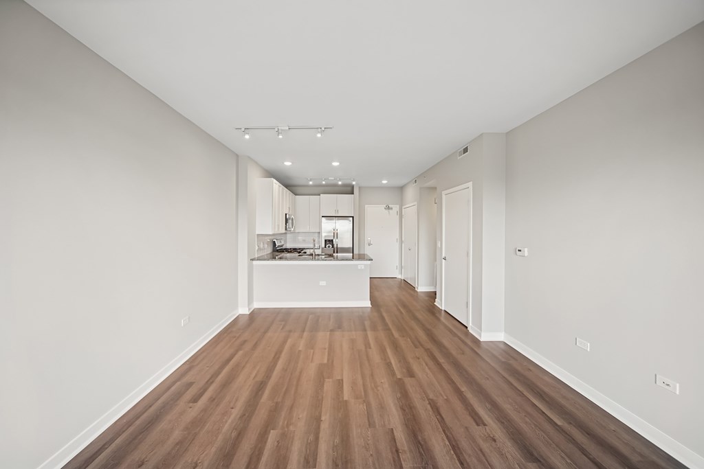 A long, empty hallway with wooden floors and white walls.