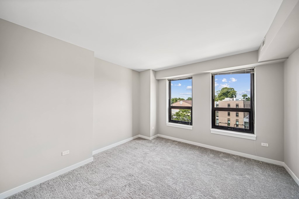 A room with a carpeted floor and a window showing a view of a building.