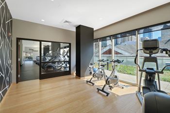 a gym with cardio machines and a window with a view of the city