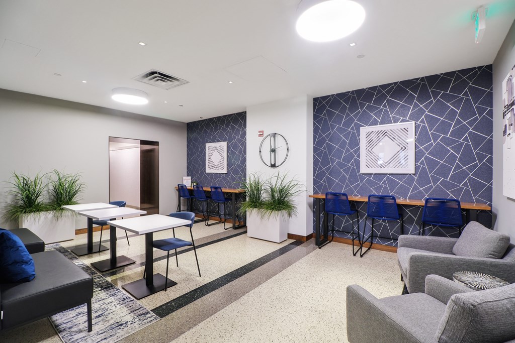 a seating area with tables and chairs and a clock on the wall