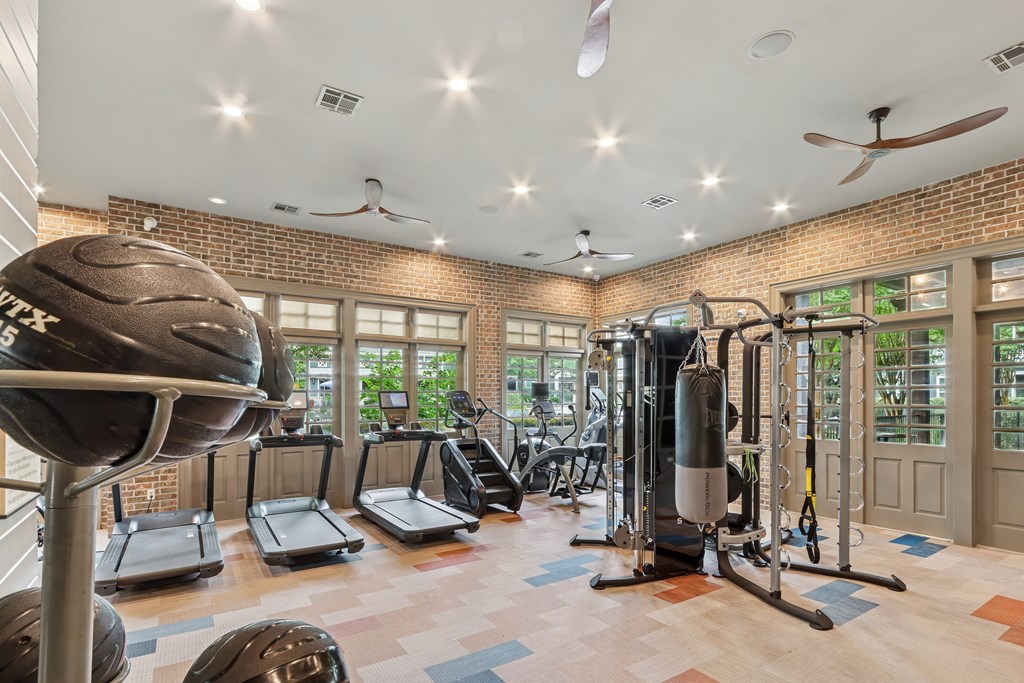 A gym with a variety of equipment including treadmills, a punching bag, and a weight machine.
