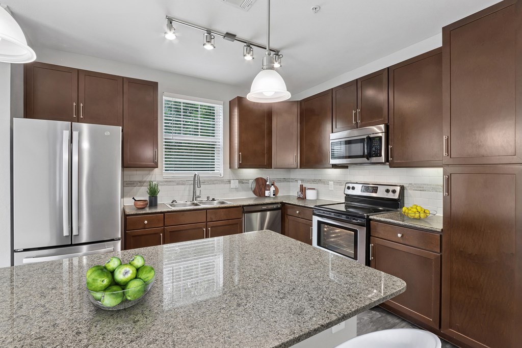 A kitchen with brown cabinets and a granite countertop.