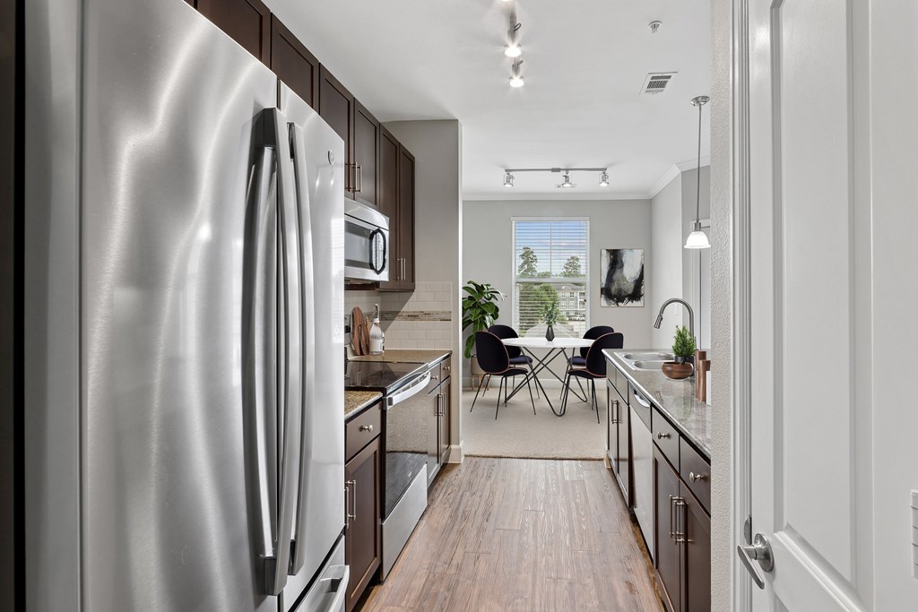 A modern kitchen with a stainless steel refrigerator and wooden flooring.