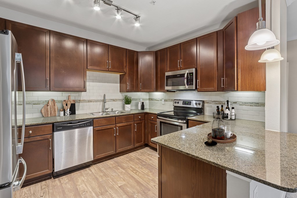 A kitchen with brown cabinets and a granite counter.