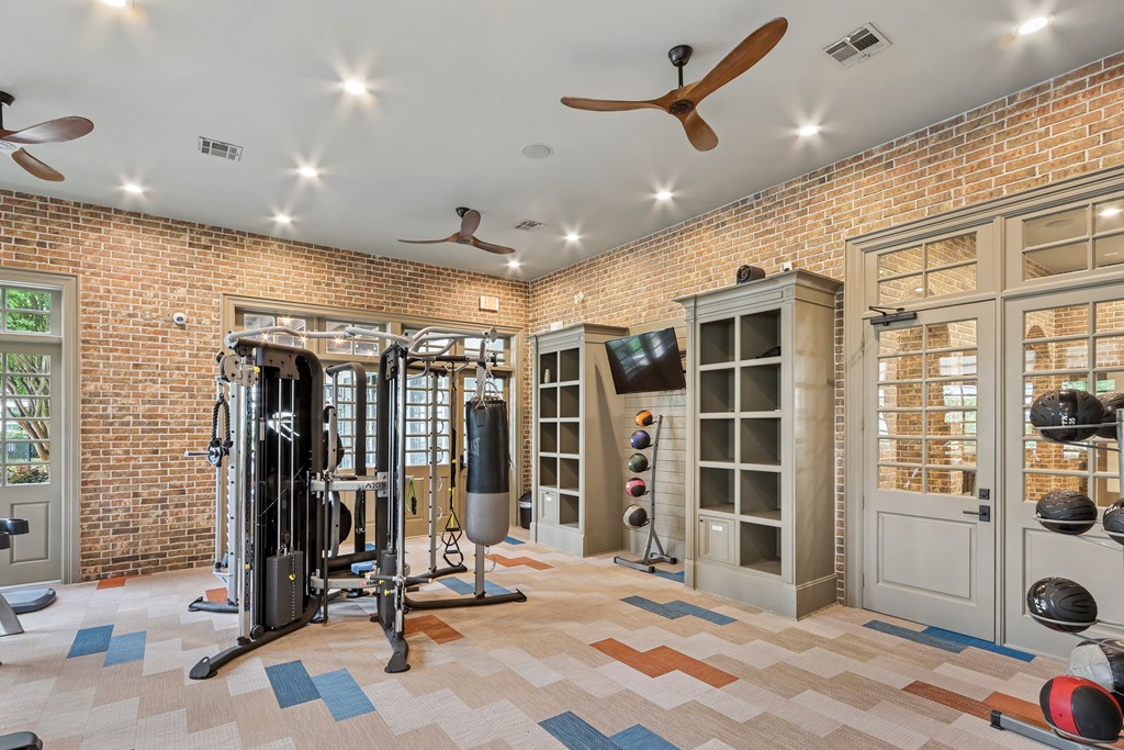 A gym with a brick wall and a variety of equipment.