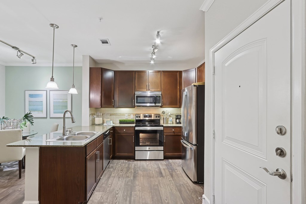A modern kitchen with dark wood cabinets and stainless steel appliances.