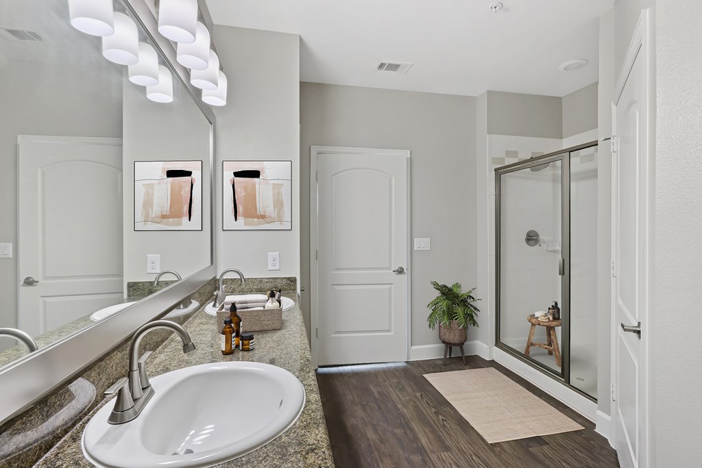 A bathroom with a sink, mirror, and wooden floor.