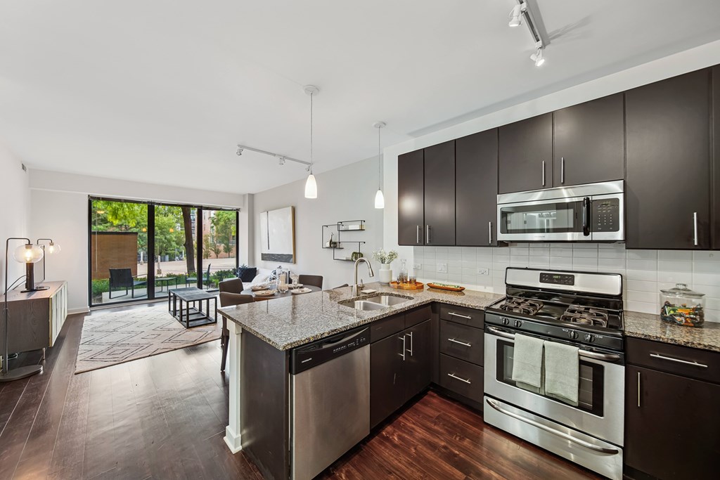 A modern kitchen with dark wood cabinets and stainless steel appliances.