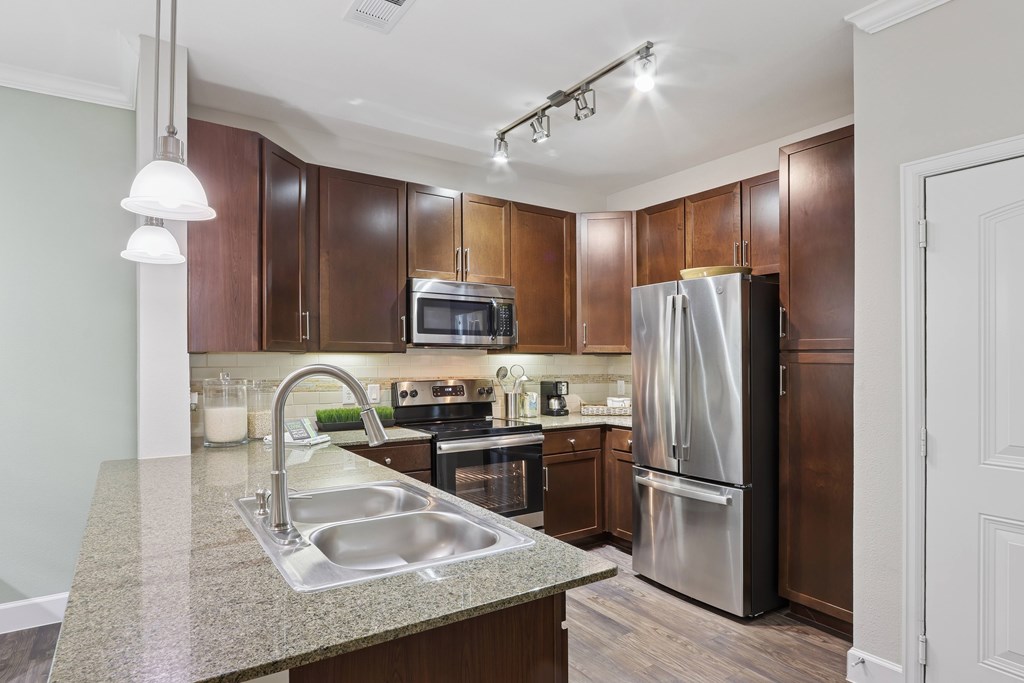 A kitchen with brown cabinets and a stainless steel refrigerator.