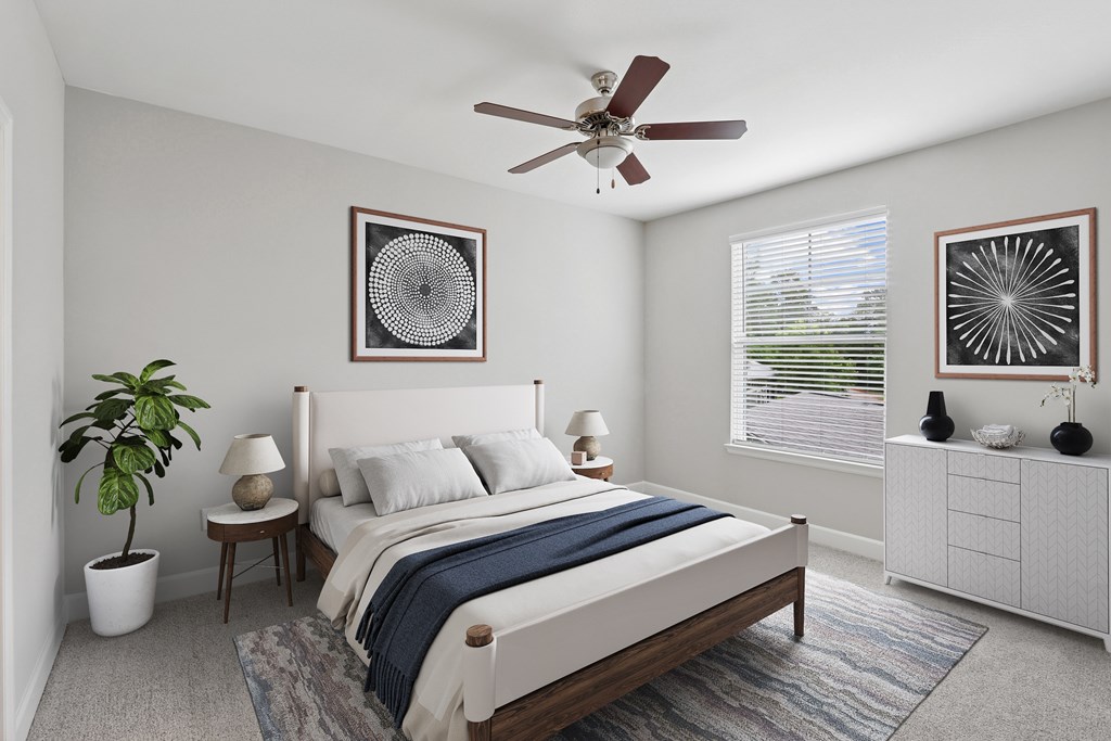 A bedroom with a bed, a ceiling fan, and two wall art pieces.