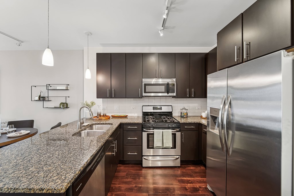 A modern kitchen with dark brown cabinets and stainless steel appliances.