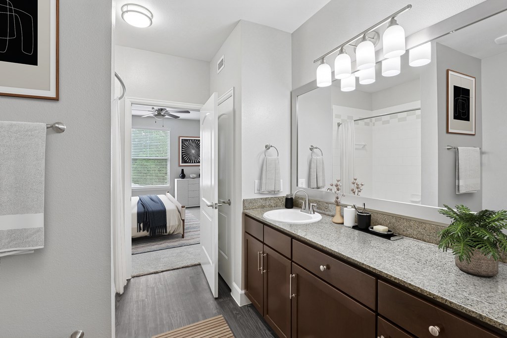 A bathroom with a white sink and brown cabinets.