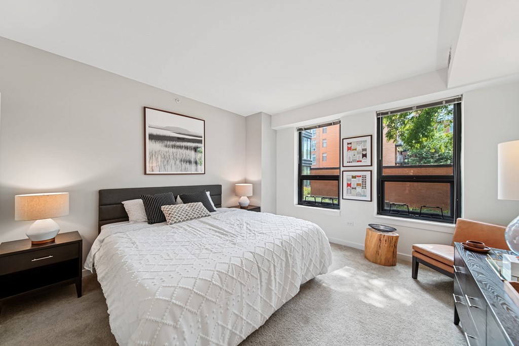 A bedroom with a large bed and a window overlooking a cityscape.
