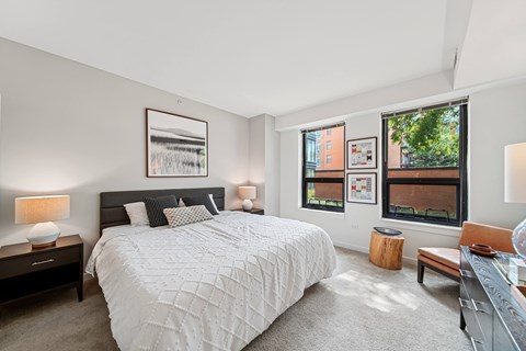 A bedroom with a large bed and a window overlooking a cityscape.