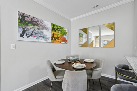 A dining room with a table set for two and a large abstract painting on the wall.