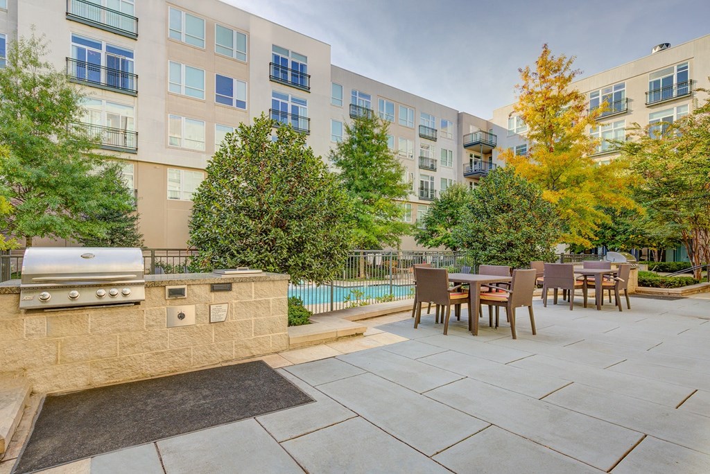 a patio with a grill and a table and chairs in front of an apartment building