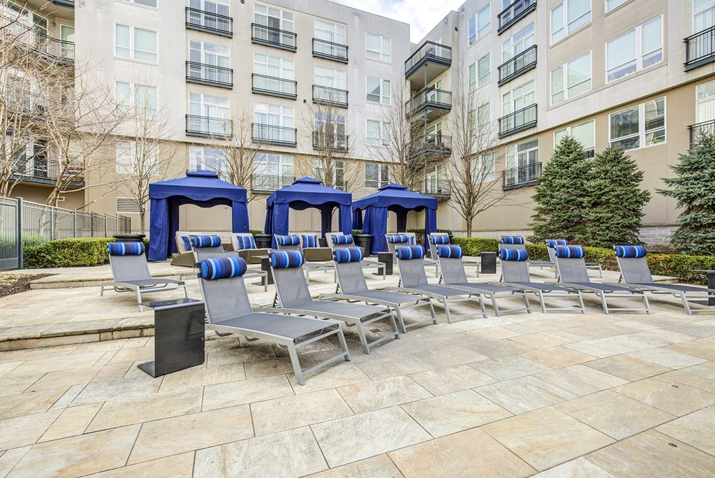 an outdoor seating area with chairs and umbrellas in front of an apartment building