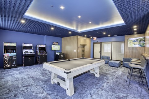 A room with a pool table and arcade games.