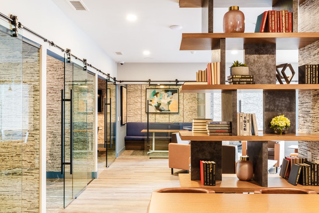a living room with a table and shelves with books at 100 House Apartments, Jersey City , New Jersey