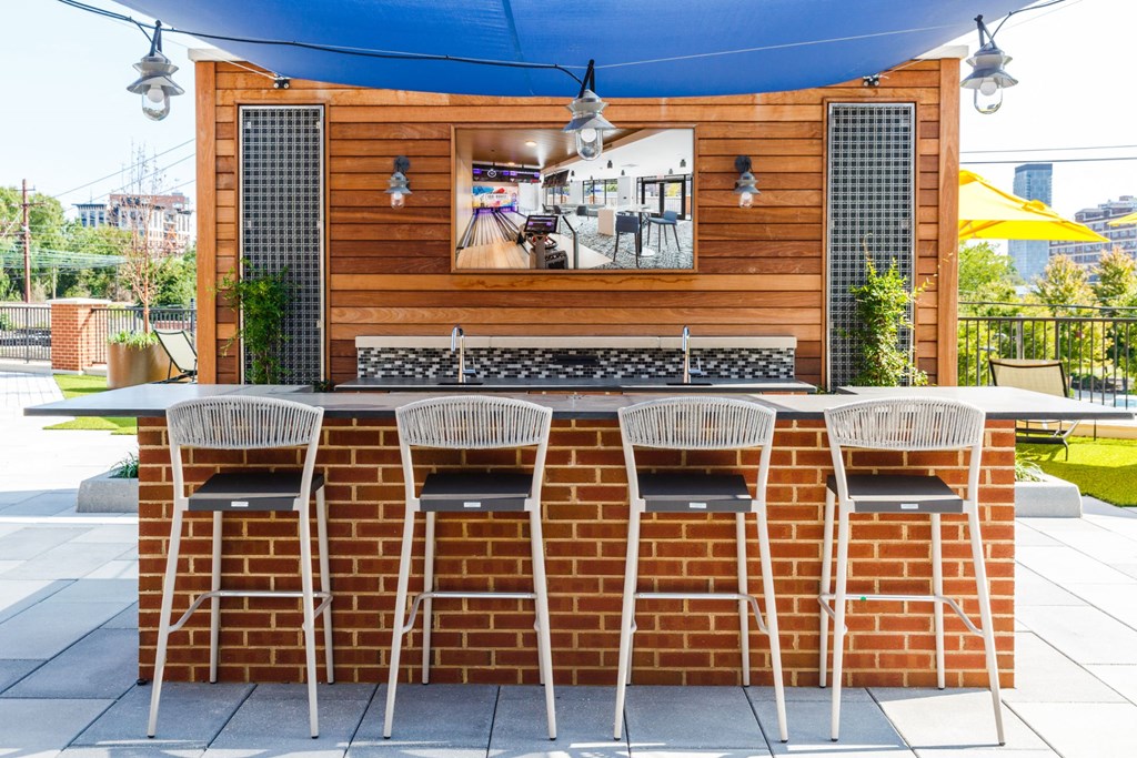 the outdoor bar area of a restaurant with a brick table and chairs at 100 House Apartments, New Jersey
