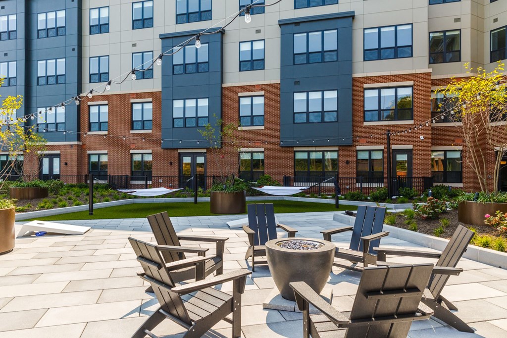 an outdoor patio with chairs and a fire pit in front of an apartment building at 100 House Apartments, Jersey City