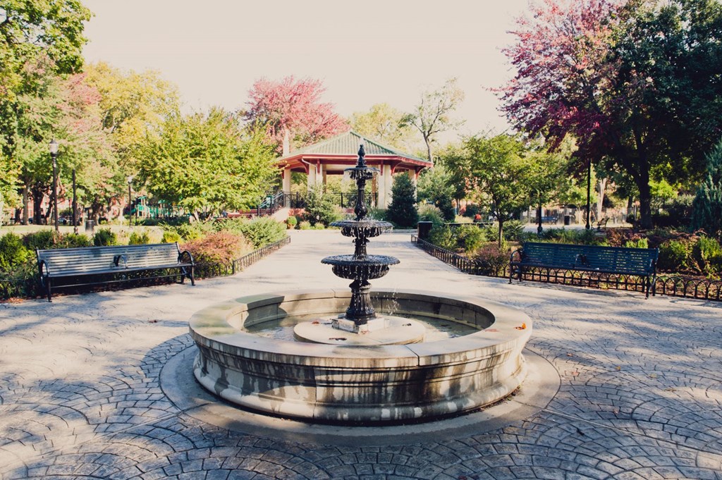 a fountain in a park with benches and a gazebo at 100 House Apartments, New Jersey, 07310