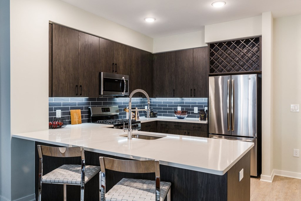 a kitchen with a large island and a stainless steel refrigerator at 100 House Apartments, Jersey City , NJ