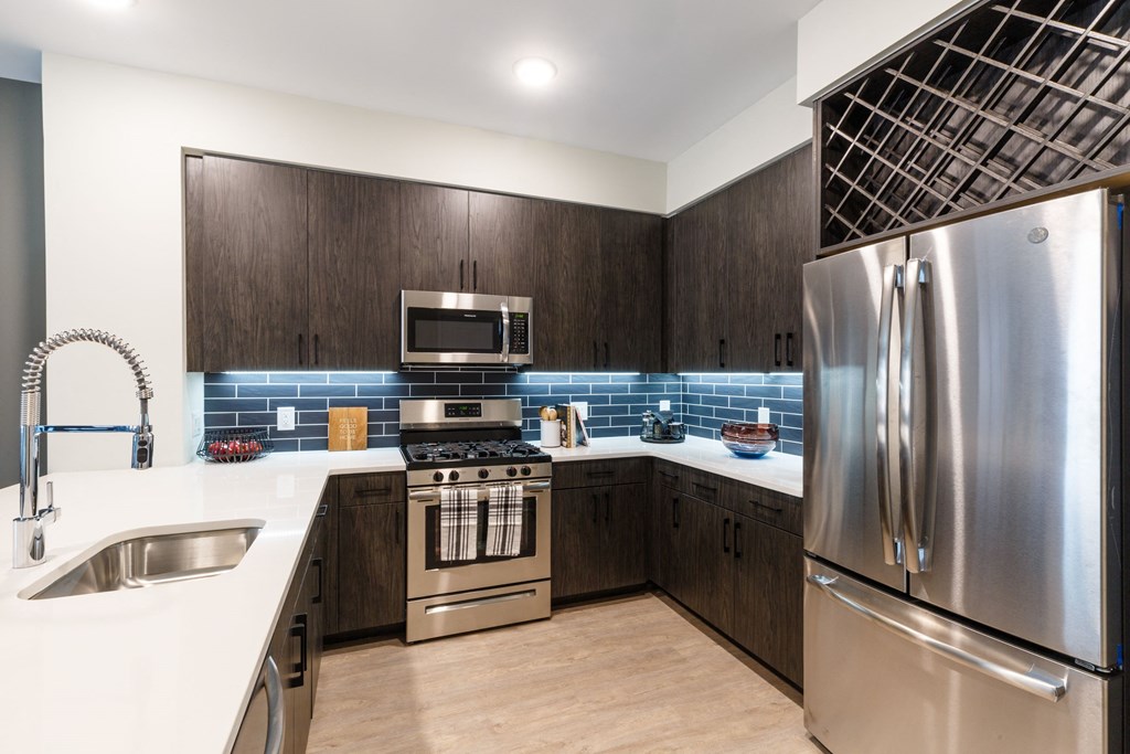 a kitchen with stainless steel appliances and wooden cabinets at 100 House Apartments, Jersey City