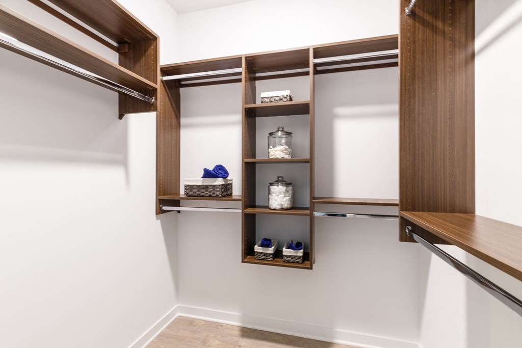 a walk in closet with wooden shelves and white walls at 100 House Apartments, Jersey City , New Jersey
