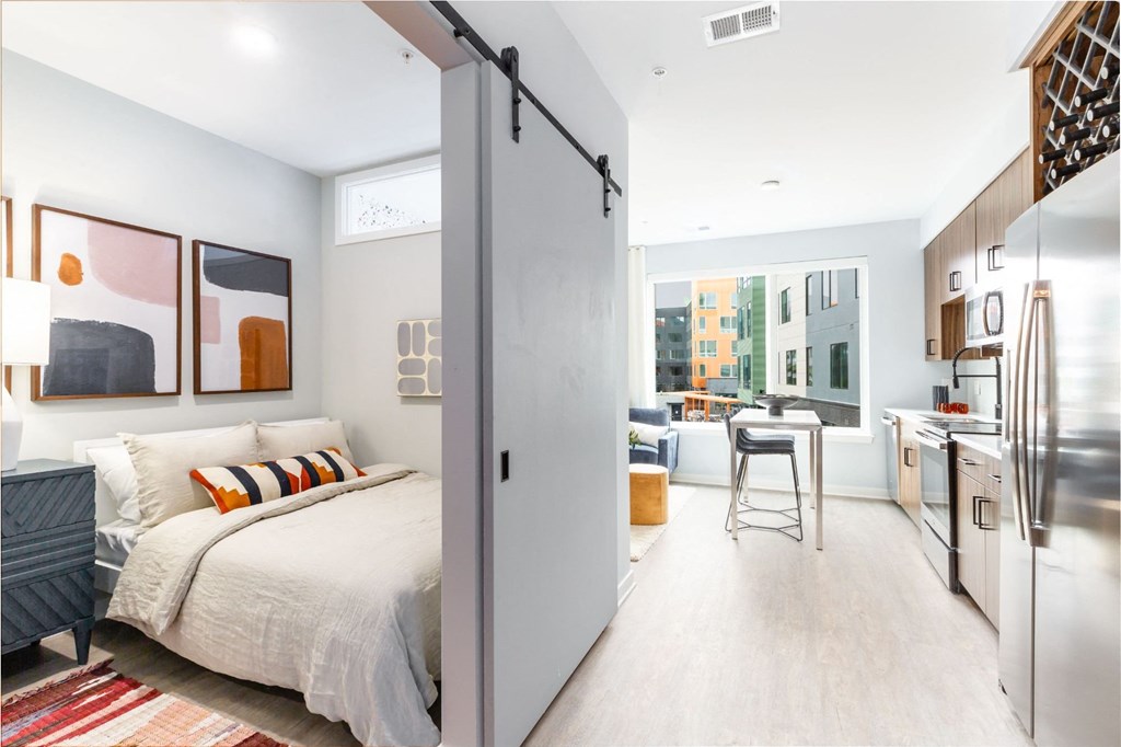 a bedroom with a bed and a kitchen next to it