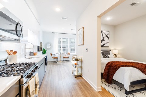 a bedroom with a bed and a kitchen with a stove at One Ten Apartments, Jersey City , New Jersey