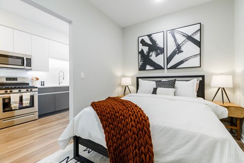 a bedroom with a large bed and a kitchen at One Ten Apartments, Jersey City