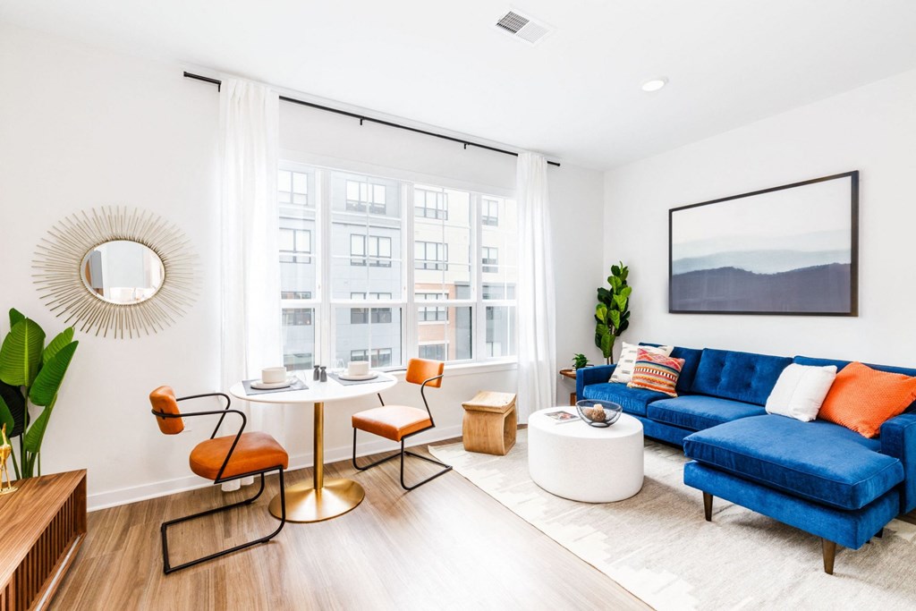 a living room with a blue couch and a round table and a large window
