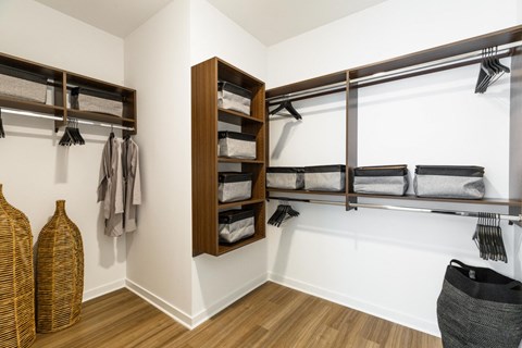 a walk in closet with wooden shelves and a white wall with a window at One Ten Apartments, Jersey City , NJ