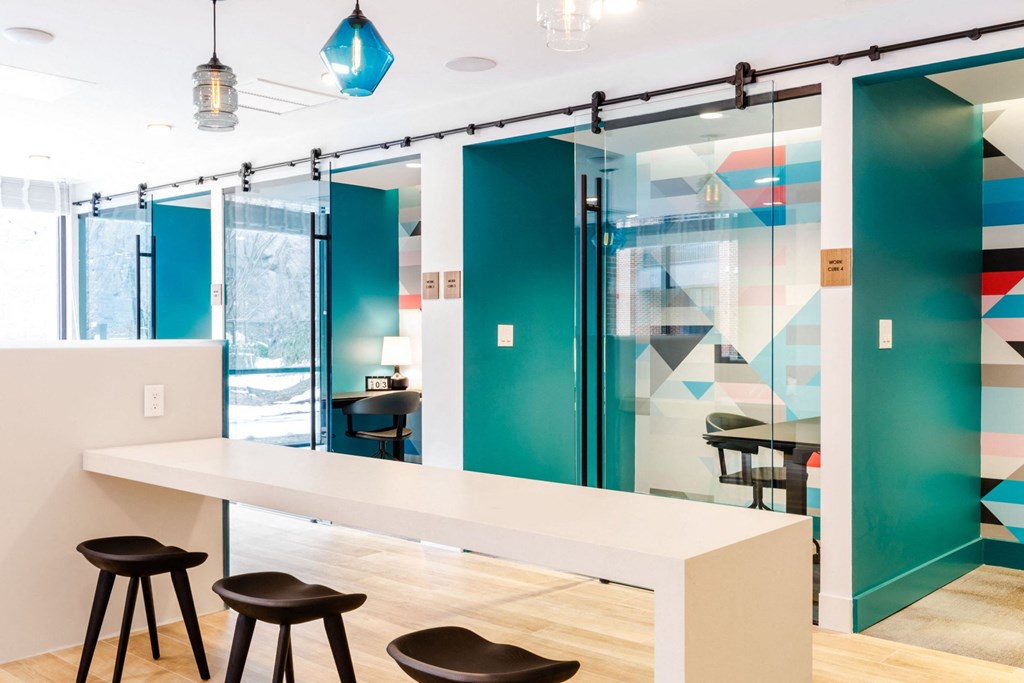 a conference room with a long white table and three black stools