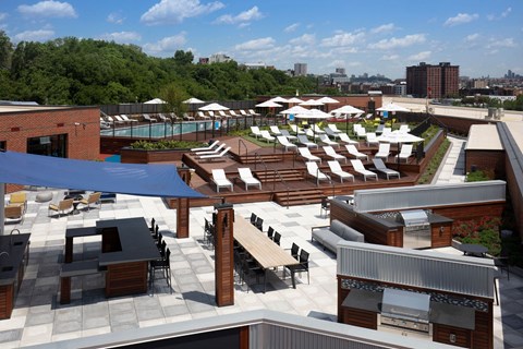 an aerial view of the rooftop lounge area of a hotel with lounge chairs and tables at One Ten Apartments, Jersey City