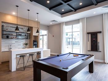 a pool table in a living room with a bar and a kitchen