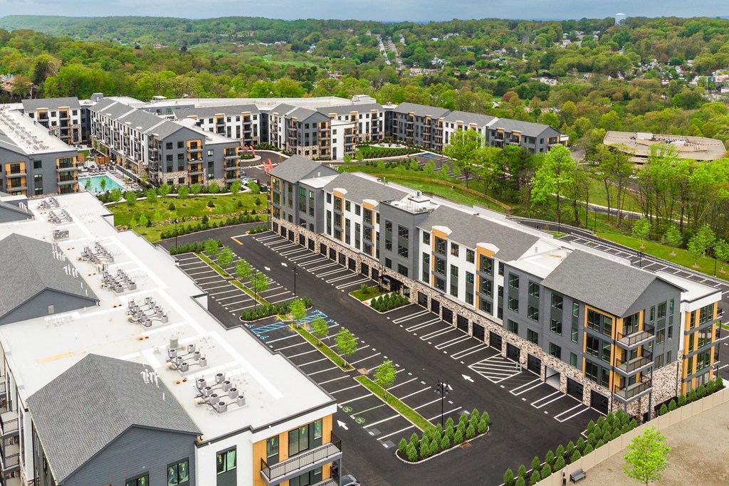 an aerial view of a development of apartments with parking lot and trees