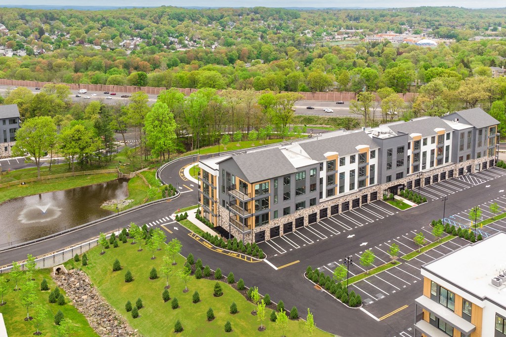 an aerial view of an apartment building with a parking lot and a river