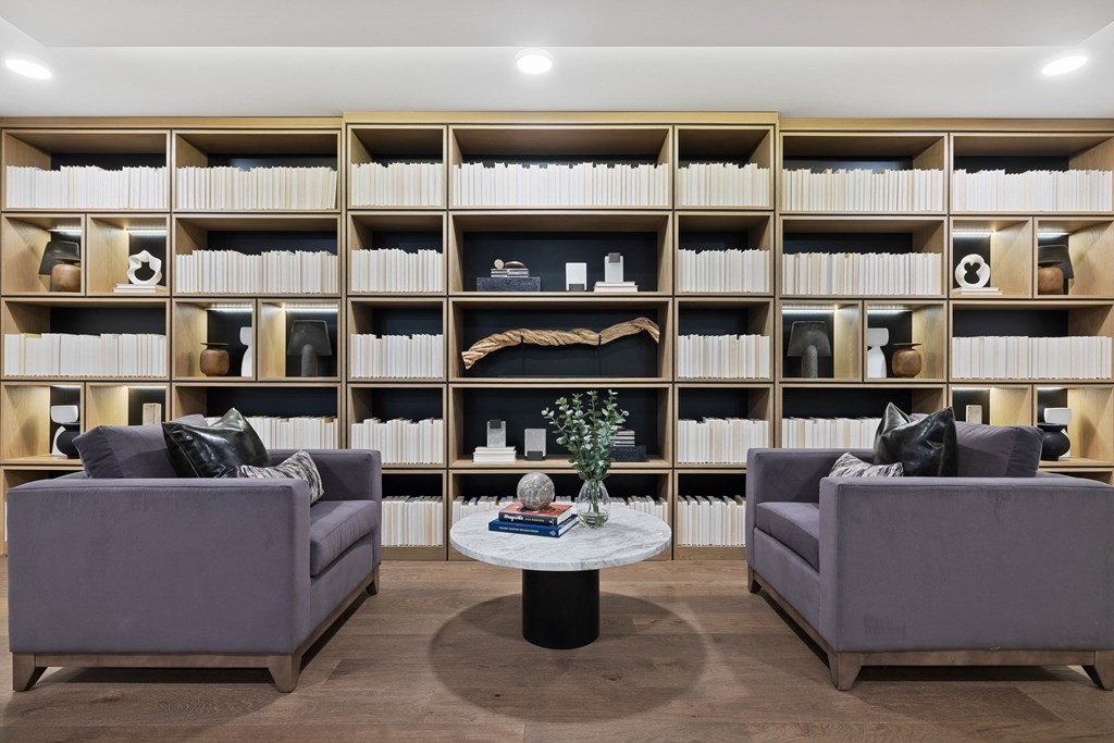 a living room with two couches and a table in front of a book shelf