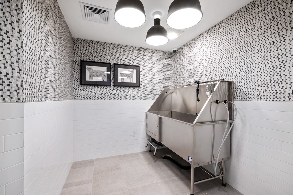 a stainless steel bath tub in a bathroom with white tiled walls and a wall