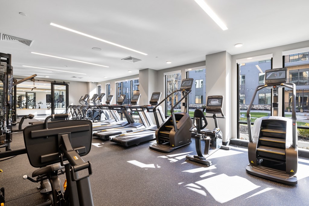 a gym with cardio equipment and windows in a building