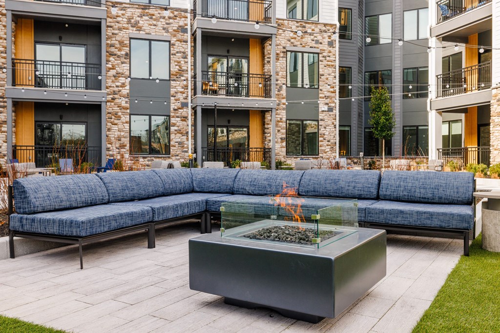 an outdoor patio with couches and a fire pit in front of an apartment building