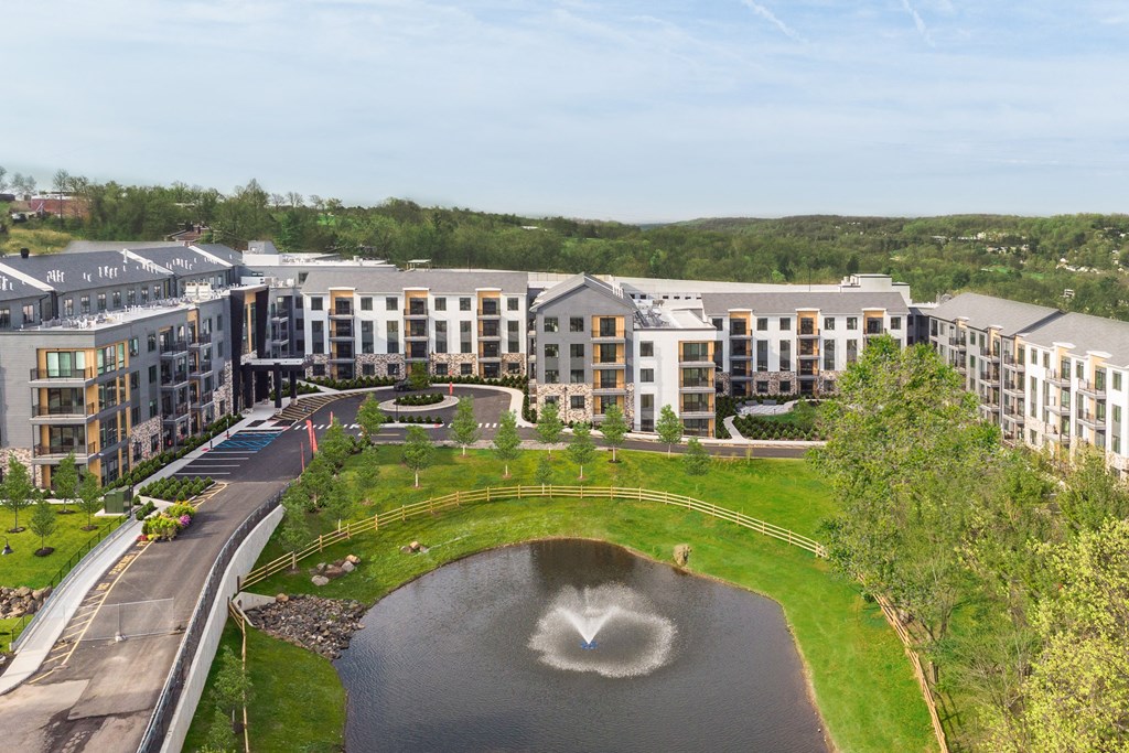 an aerial view of a building with a fountain in the middle of a pond