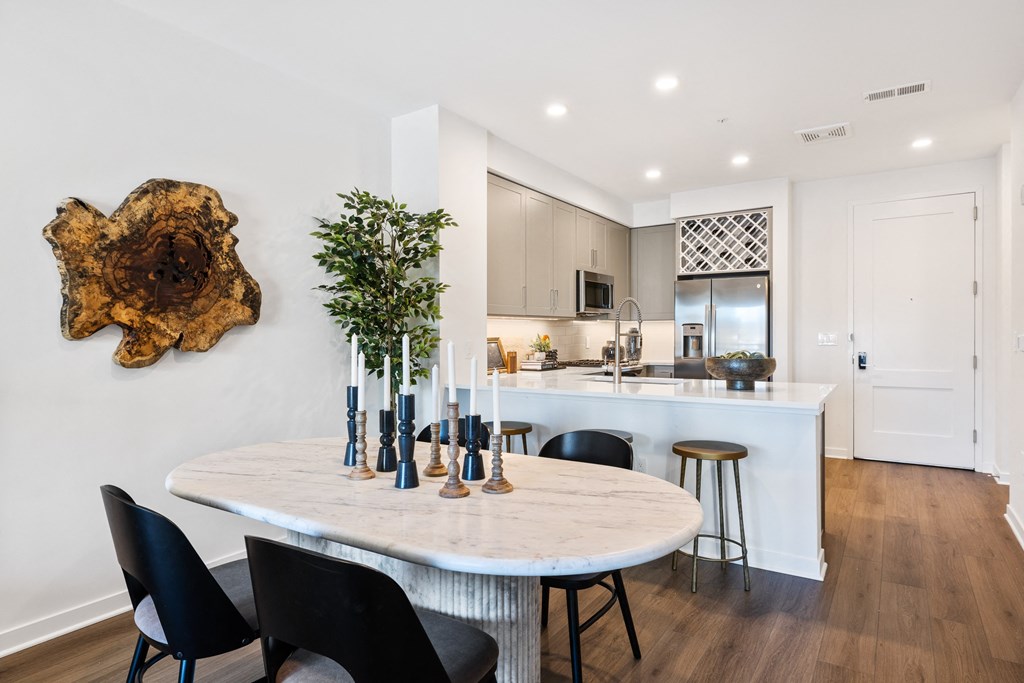 an open kitchen and dining area with a marble table and black chairs