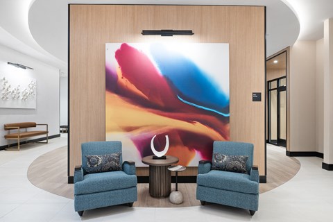 a lobby with two blue chairs and a large painting on the wall at The Ivy, Chatham, NJ