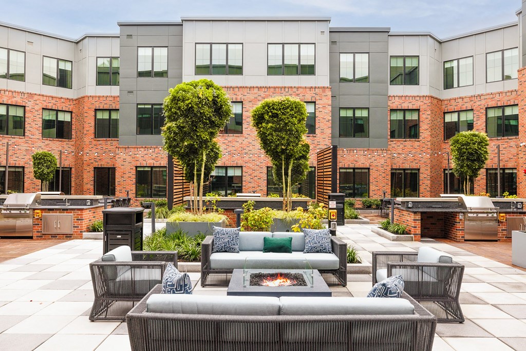 an outdoor lounge area with couches and a fire pit in front of a building at The Ivy, Chatham, NJ 07928