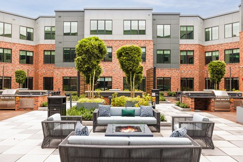 an outdoor lounge area with couches and a fire pit in front of a building at The Ivy, Chatham, NJ 07928