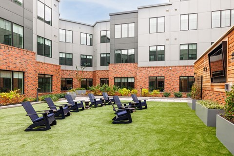 an outdoor patio with blue chairs in front of an apartment building at The Ivy, New Jersey, 07928