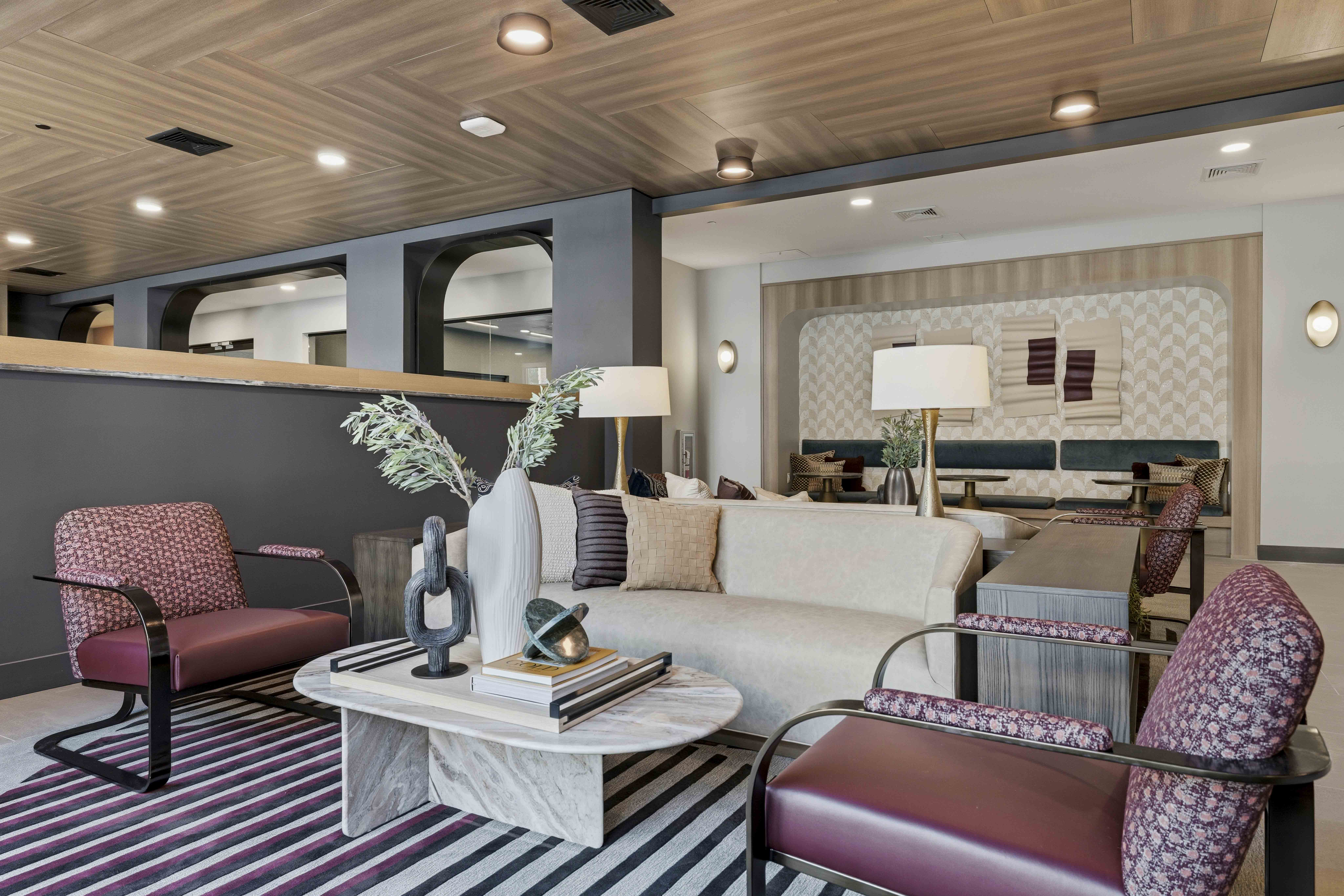 A living room with a white sofa, a red chair, and a coffee table with a vase of flowers on it.